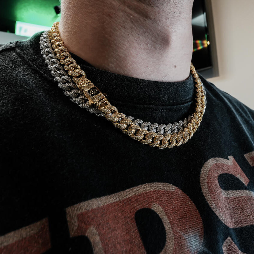 a gold and silver chain cuban link necklaces on a person wearing a black shirt with red text.