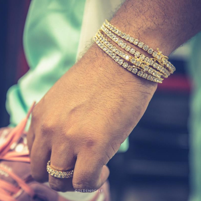 Person wearing multiple gold tennis bracelets on a wrist