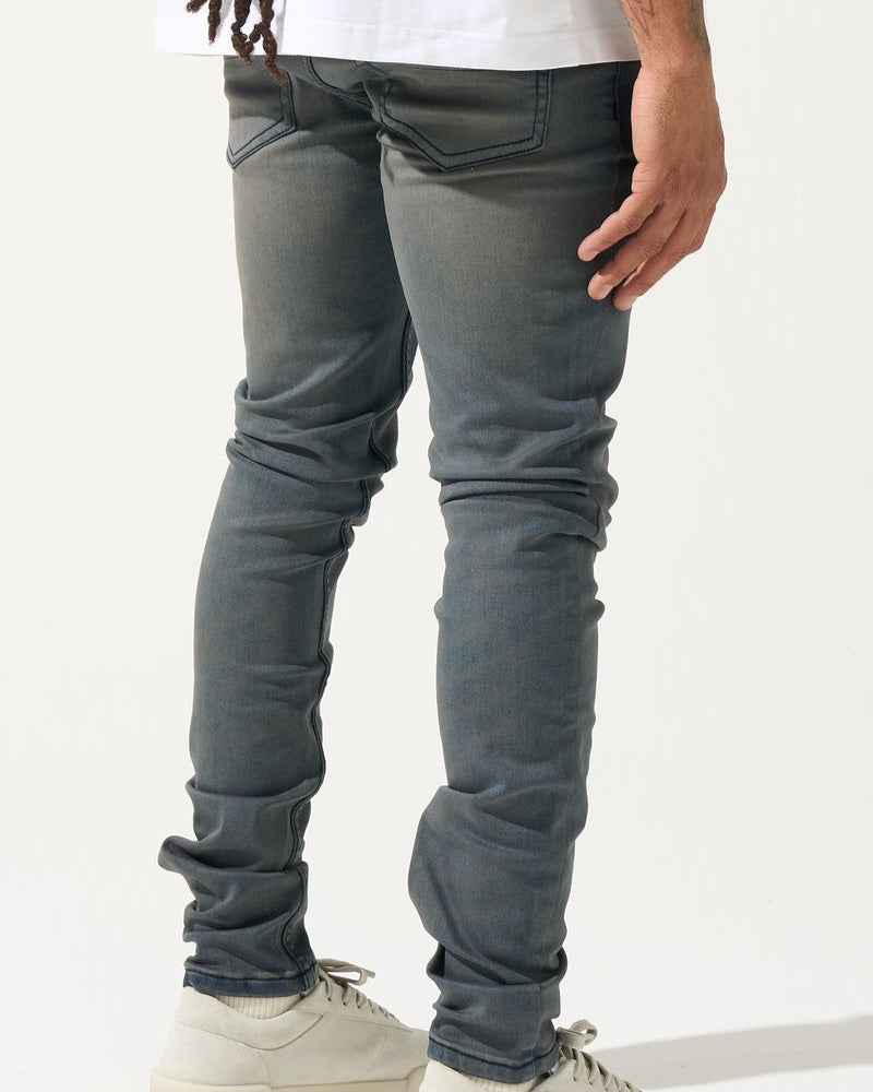 Person wearing gray jeans and white sneakers on a white background