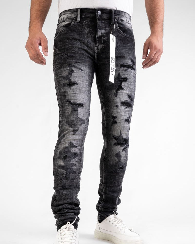 Person wearing black distressed jeans with a visible brand tag on a white background