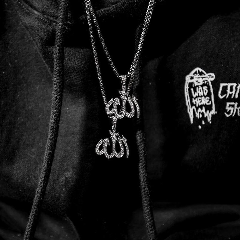 close up of a person in a Black hoodie wearing a silver Allah necklace and text design on a dark background