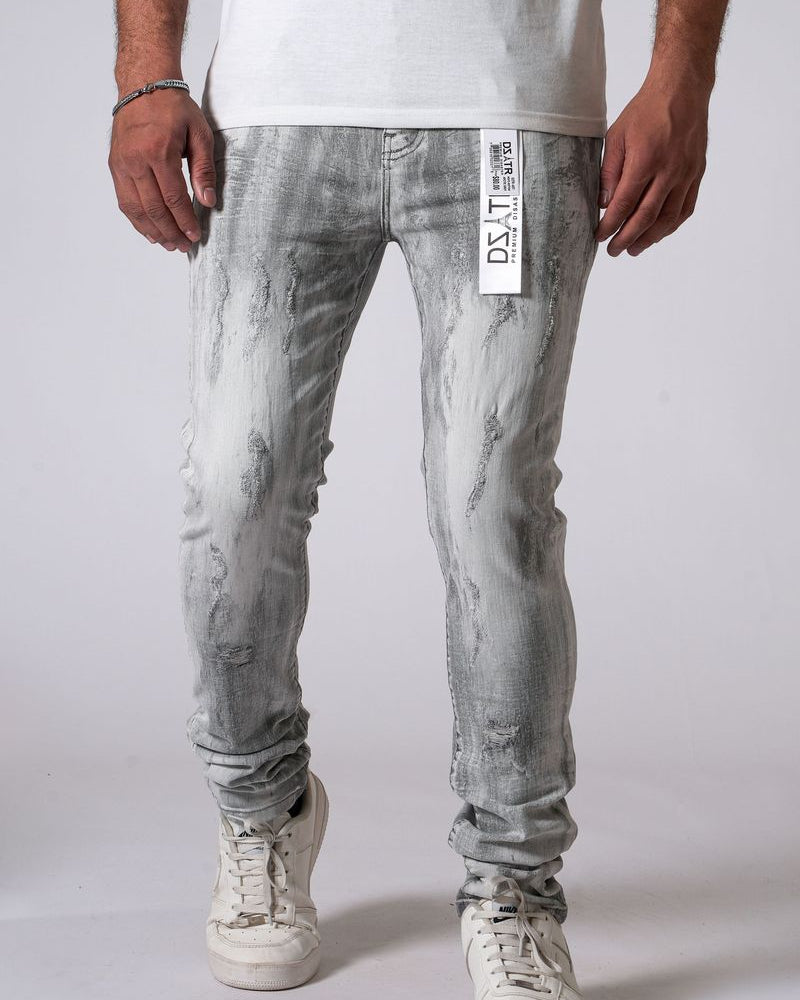 Person wearing light gray distressed jeans and white sneakers on a plain background