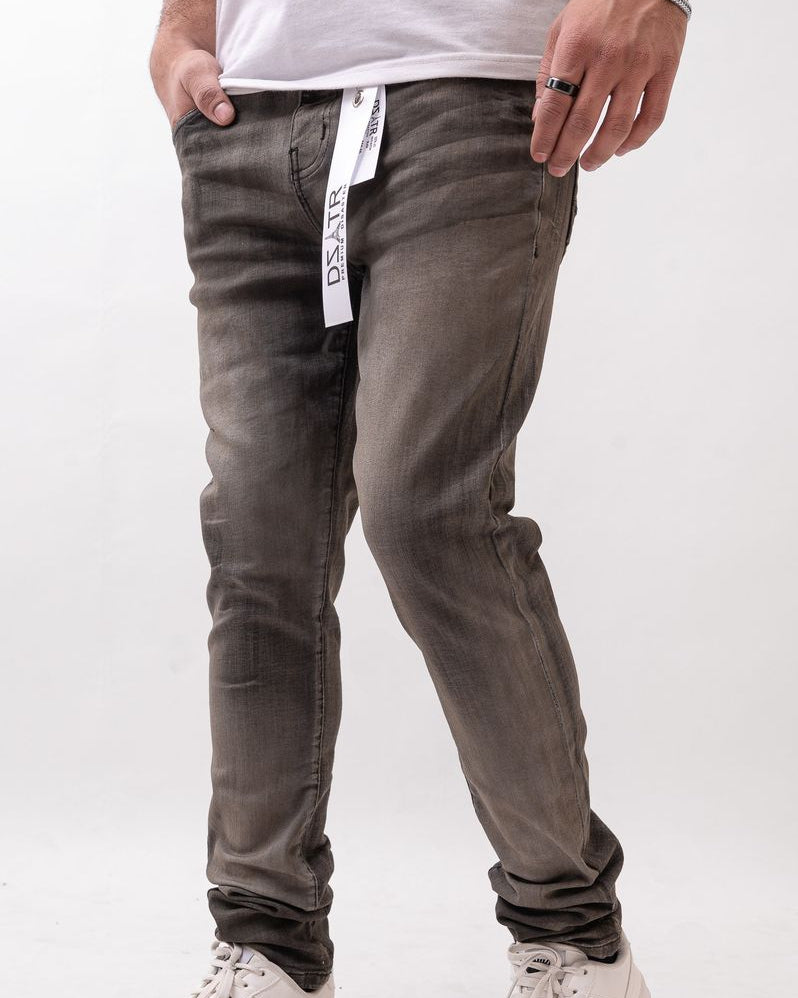 Person wearing gray jeans with a white label and white sneakers on a light gray background