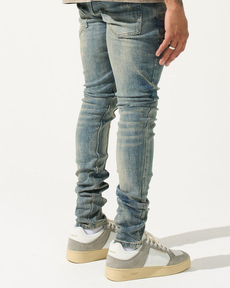 Person wearing light blue jeans and gray sneakers on a white background