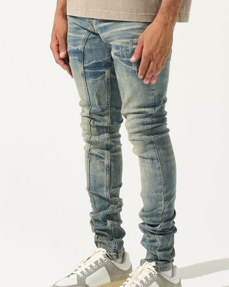 Person wearing light blue distressed jeans and gray sneakers on a white background