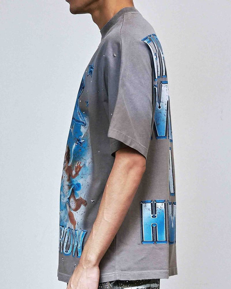 Person wearing a gray t-shirt with colorful graphic designs on a plain background