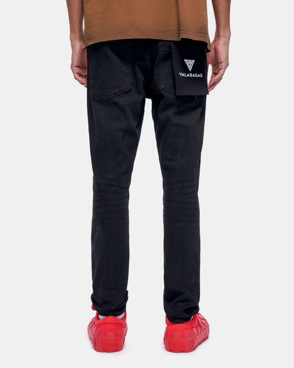 Person wearing black pants with a brand logo, brown shirt, and red shoes on a white background