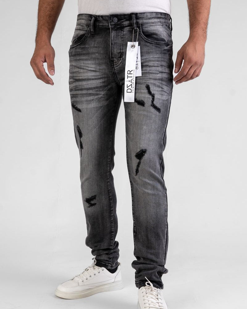 Person wearing gray distressed jeans with a brand tag on a white background