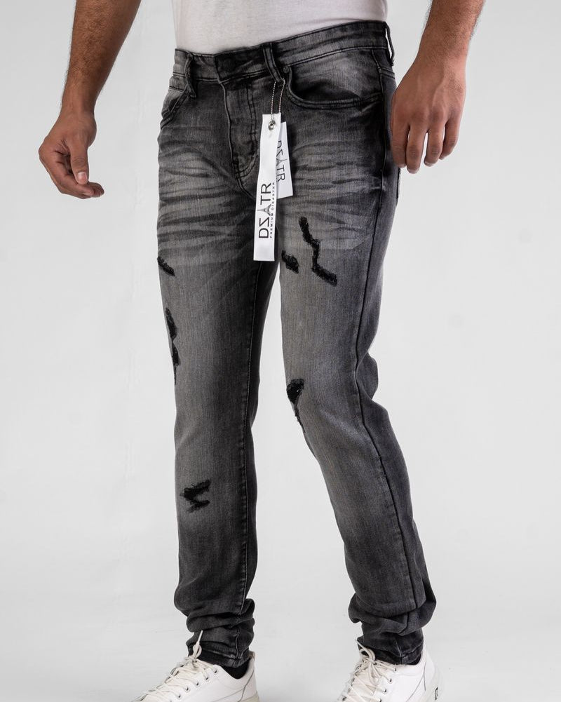 Person wearing black distressed jeans with a visible brand tag on a white background