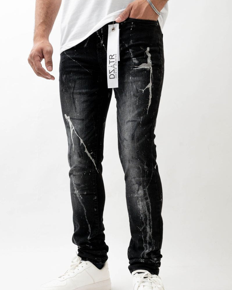 Person wearing black marble effect jeans with a visible brand tag on a white background