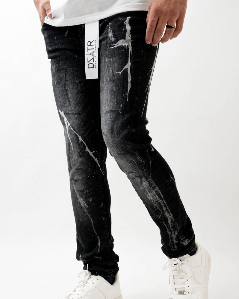 Person wearing black distressed jeans with a visible brand logo on a white background