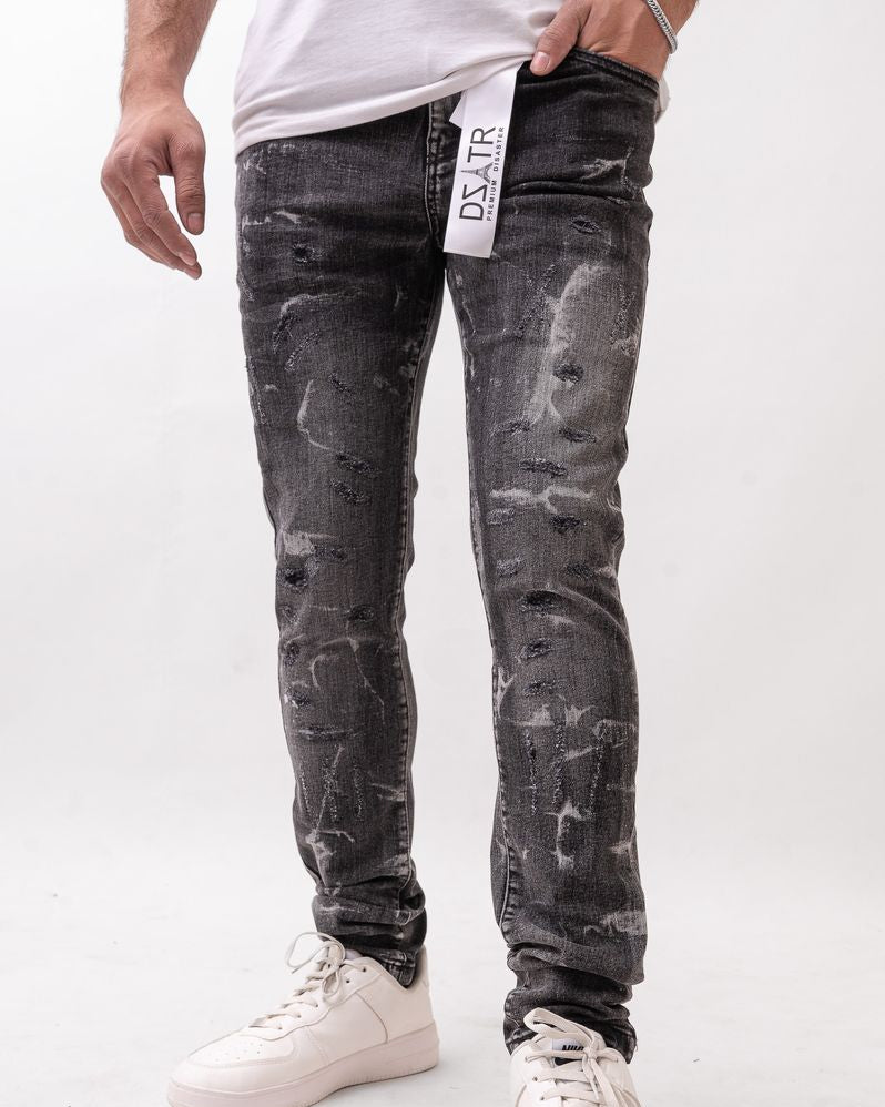 Person wearing black distressed jeans with a visible brand label on a white background