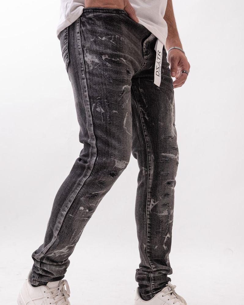 Person wearing black acid-wash jeans and white sneakers on a white background