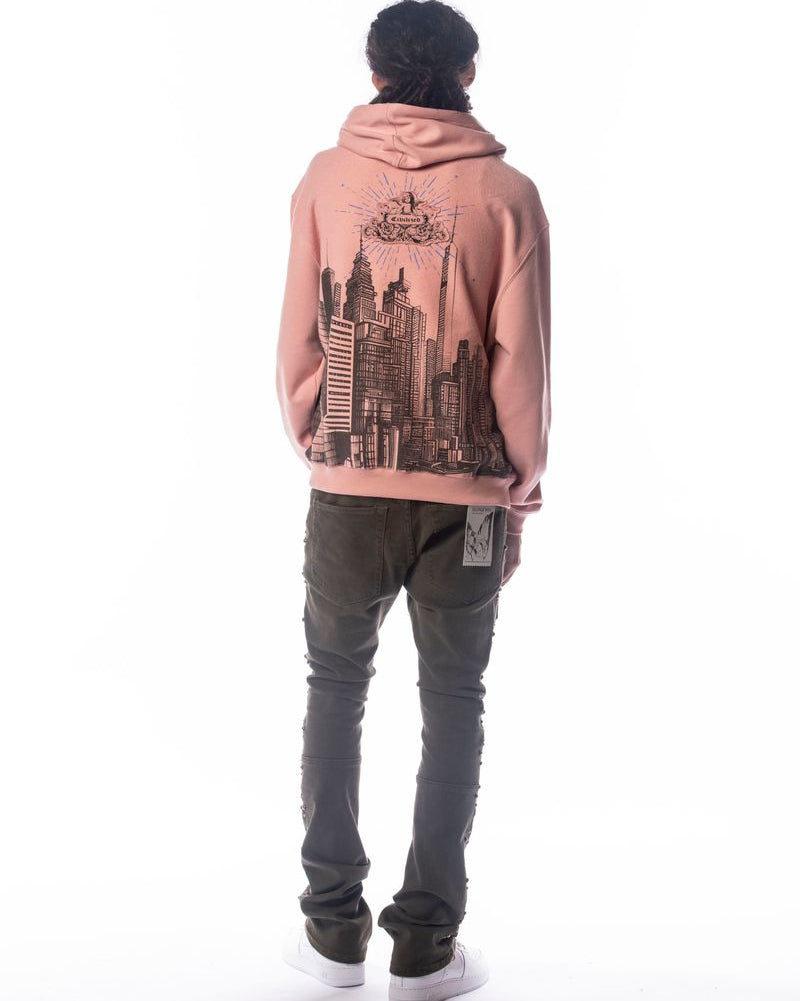 Person wearing a pink hoodie with a cityscape design on the back, standing against a white background