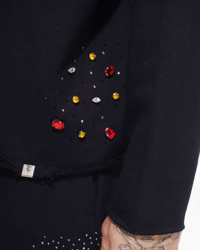 Black garment with colorful embellishments on a plain background