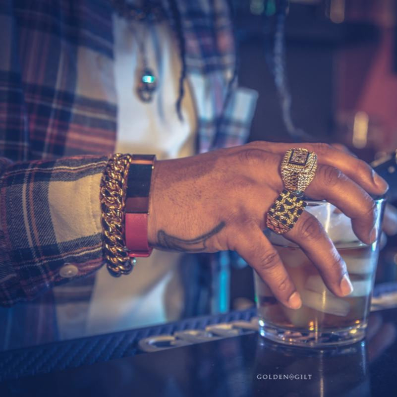Close-up of a hand wearing the gold championship ring with diamonds, with a blurred bar background.