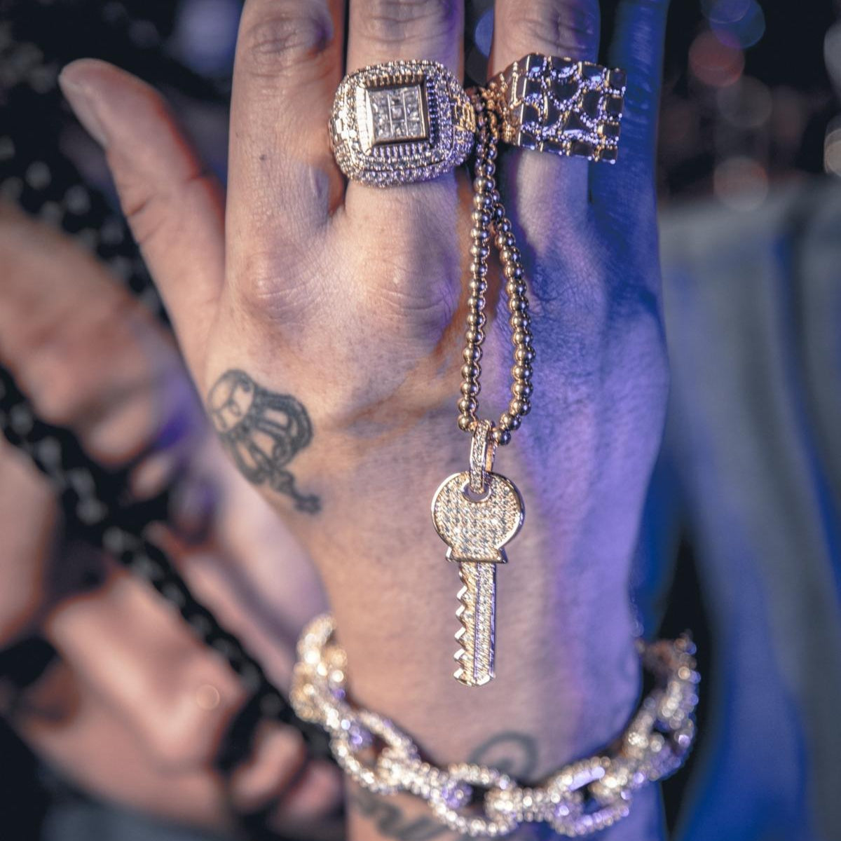 Close-up of a hand wearing the gold championship ring with diamonds, with a blurred background.
