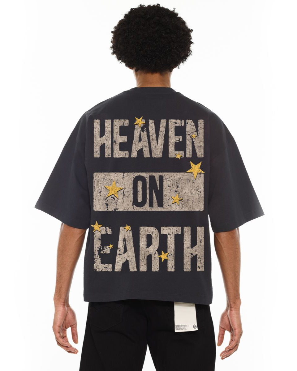 Person wearing a black t-shirt with 'Heaven on Earth' text and stars on the back.