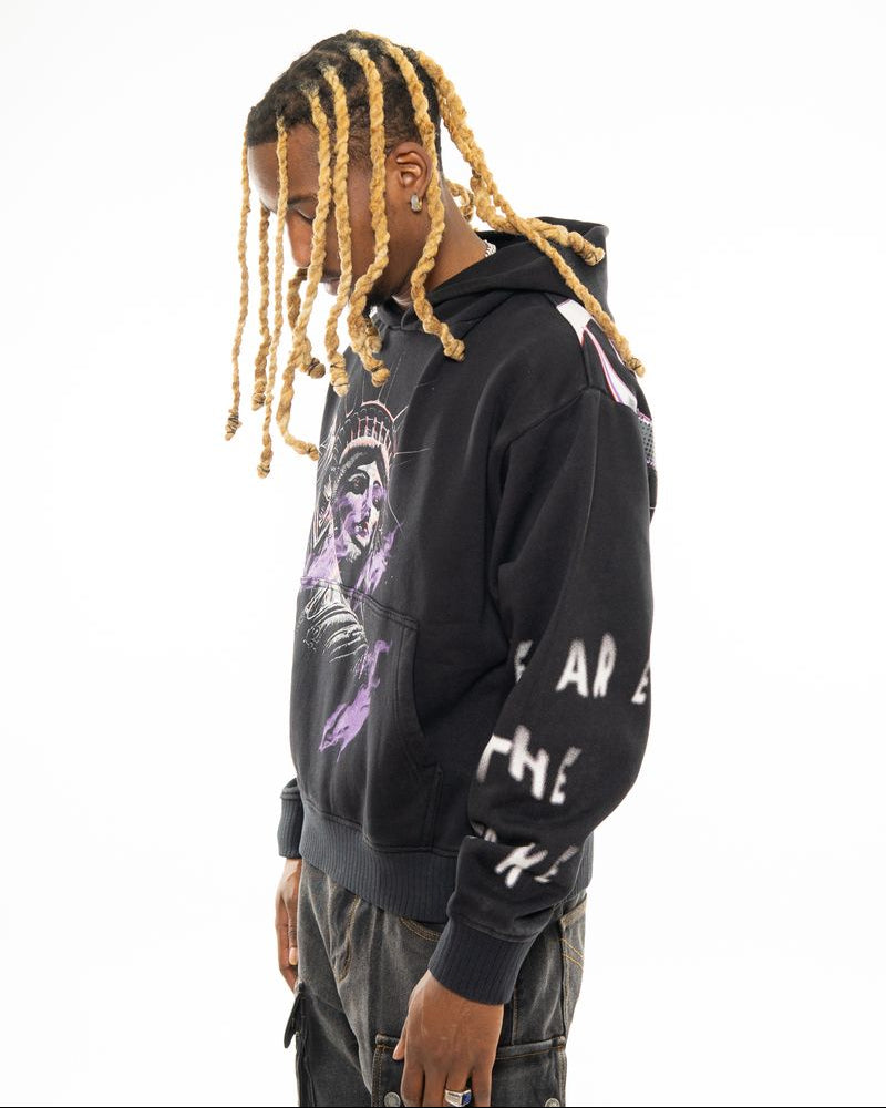 Person wearing a black hoodie with graphic designs on a white background