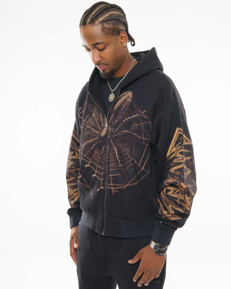 Man wearing a black hoodie with gold designs on a white background