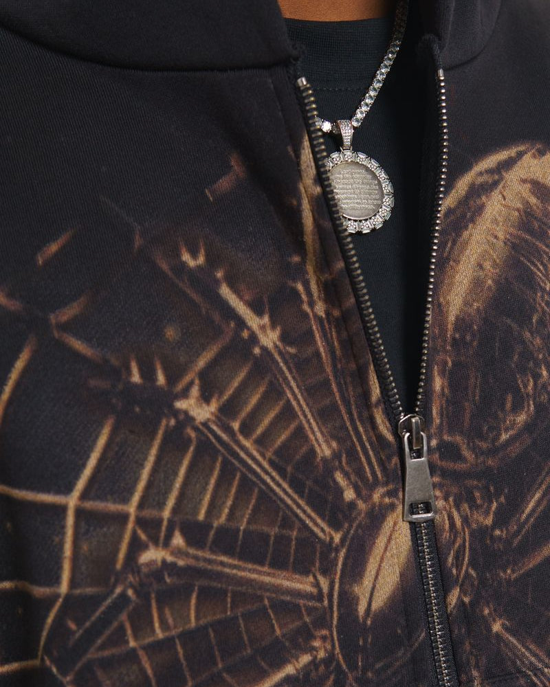 Close-up of a hoodie with a detailed pattern and a silver zipper, featuring a brand logo.