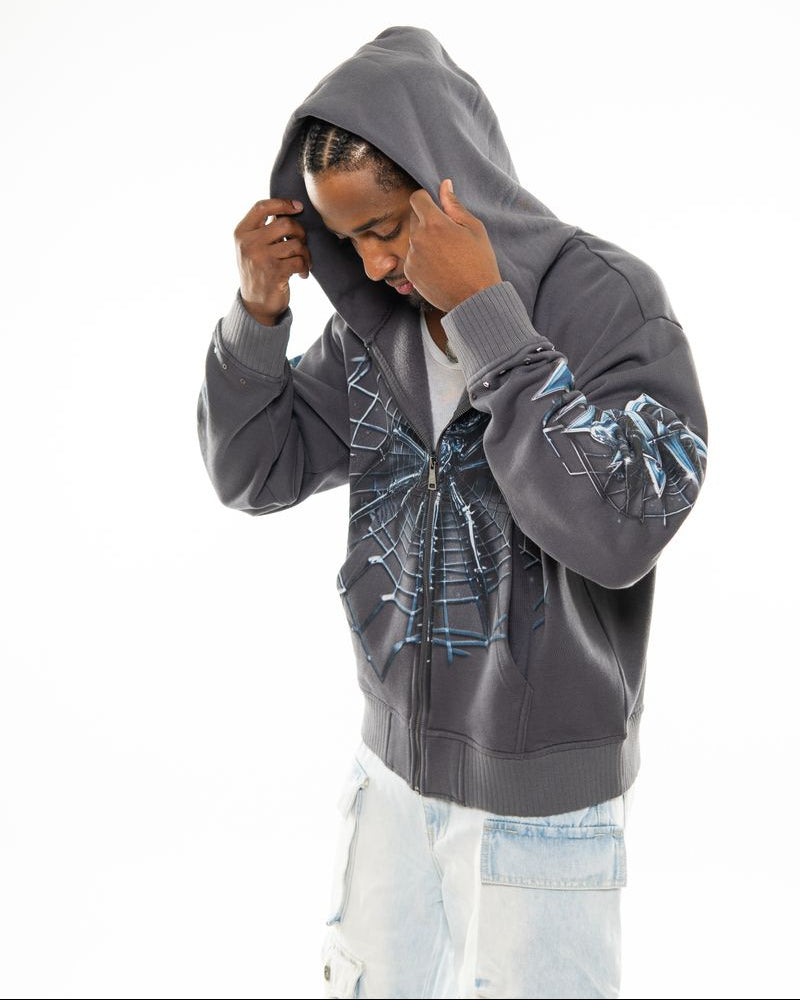 Person wearing a gray hoodie with spider web design on a white background