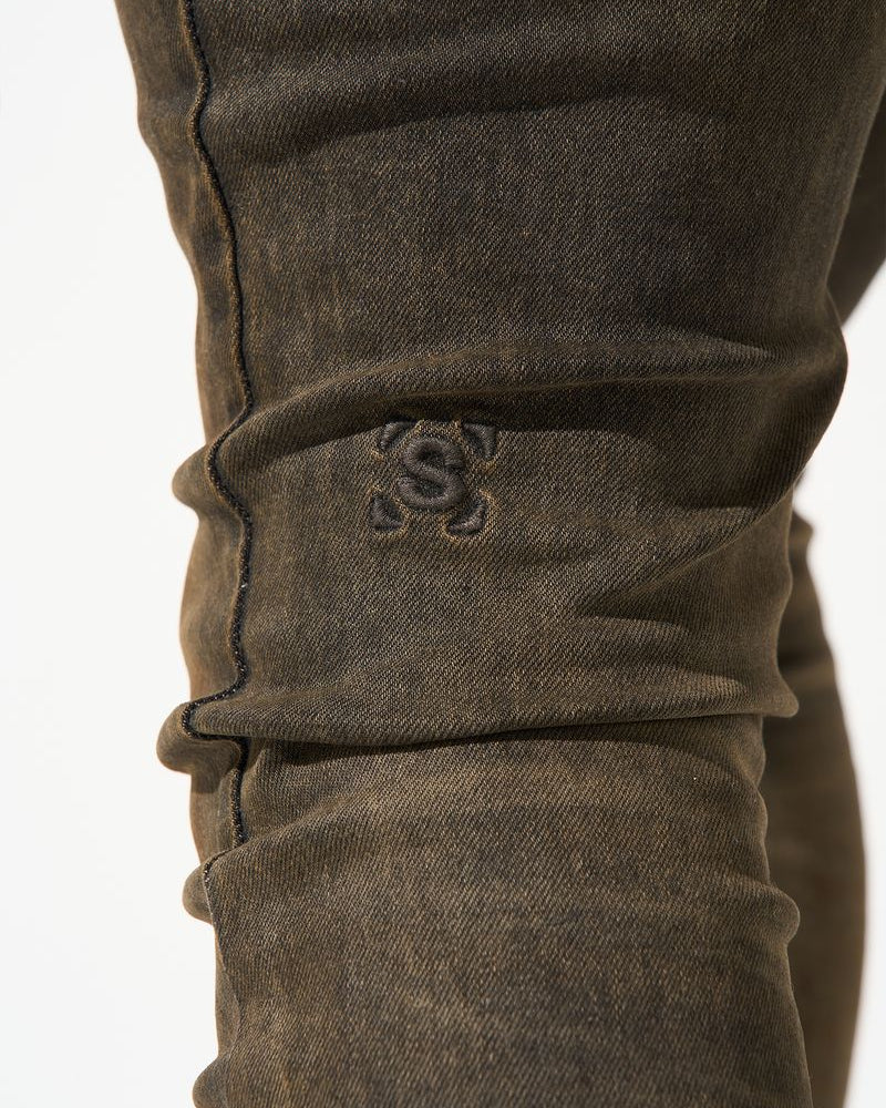 Close-up of brown pants with a logo on a white background