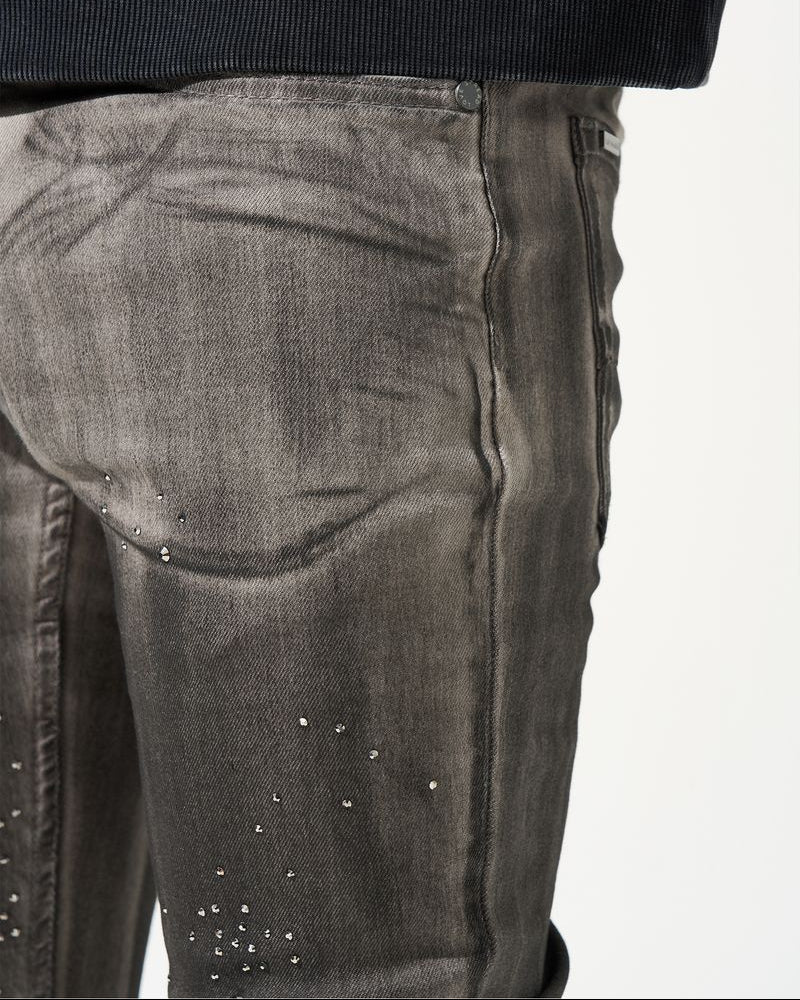 Close-up of dark gray jeans with rhinestone embellishments on a white background