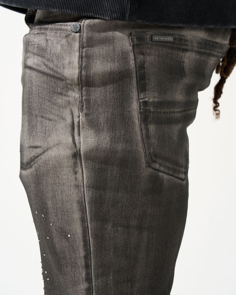 Close-up of dark gray jeans with a brand label on a white background