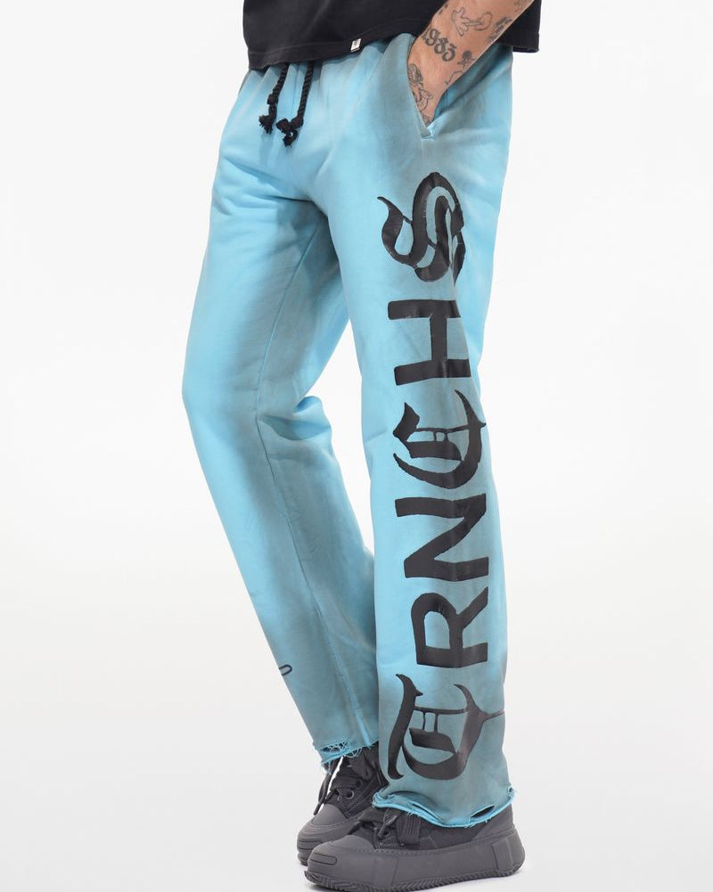 Light blue jogger pants with 'Grinch' text worn by a person on a white background