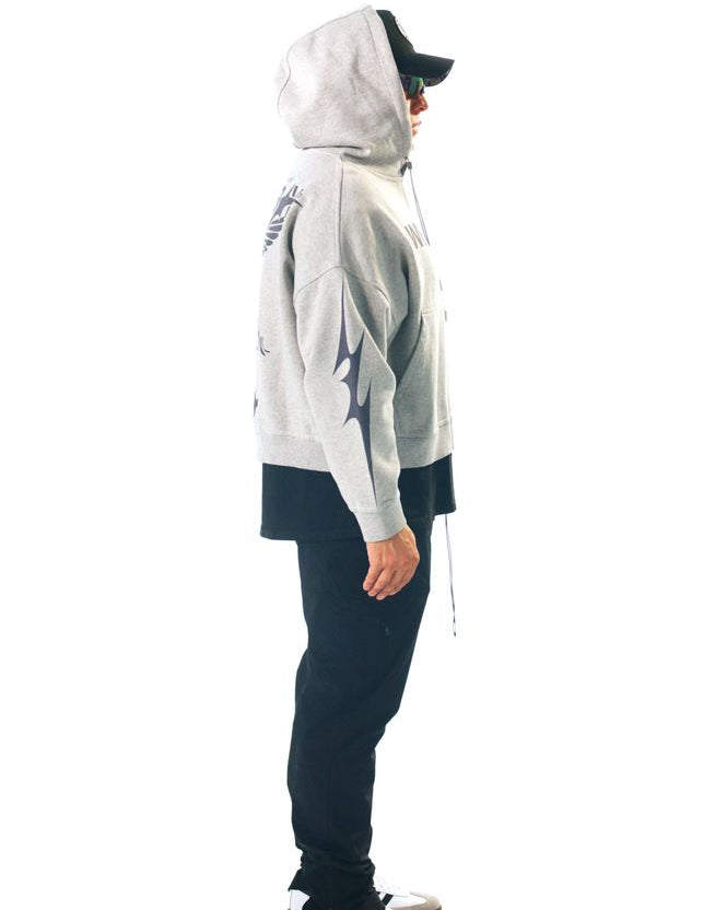 Person wearing a white hoodie with black designs and dark pants on a white background