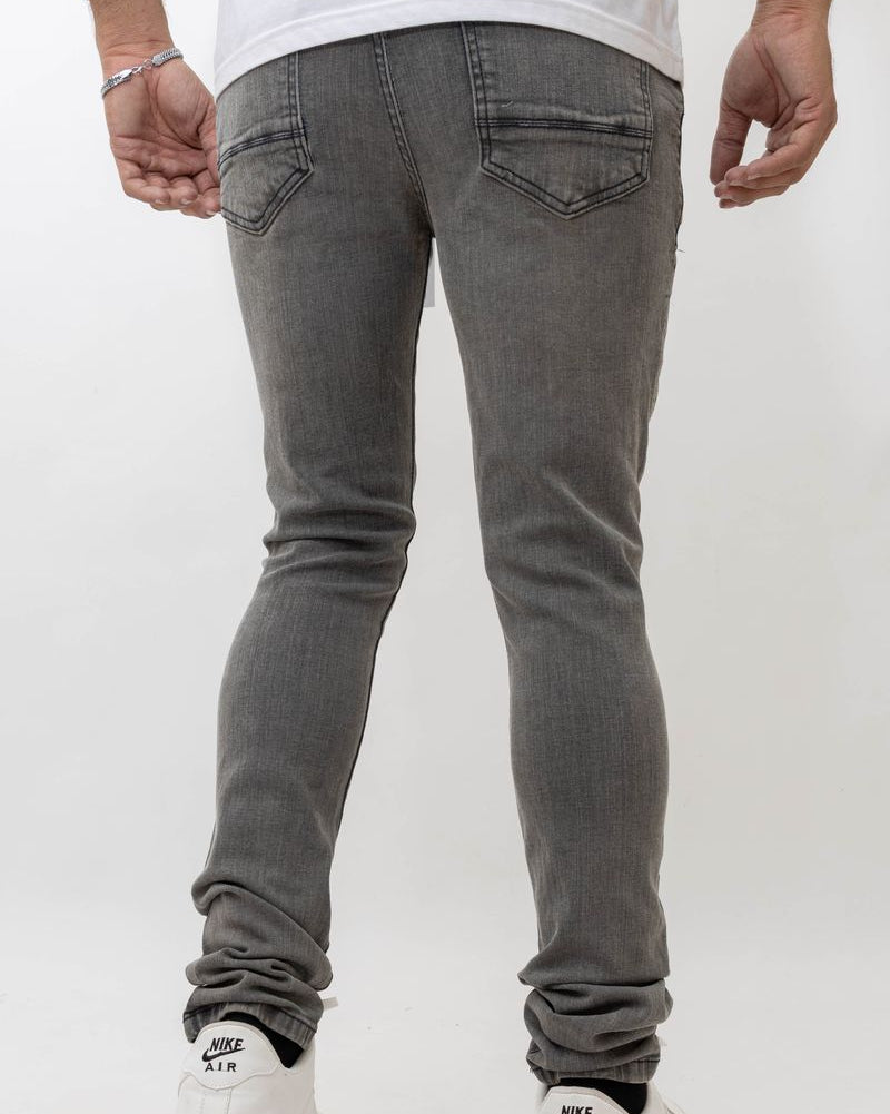 Person wearing gray jeans and white sneakers on a plain background