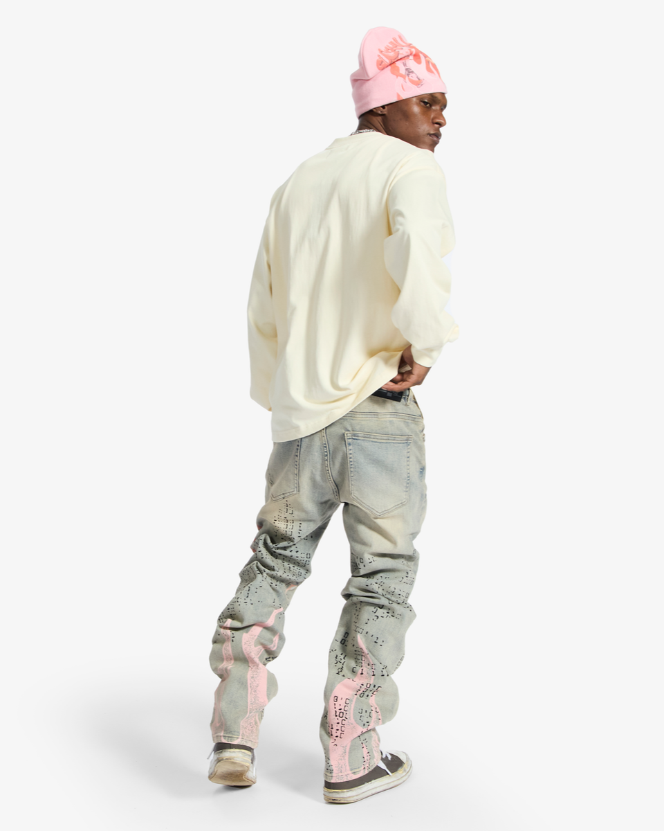 Person wearing a cream sweater, light gray jeans with pink accents, and a pink beanie on a white background