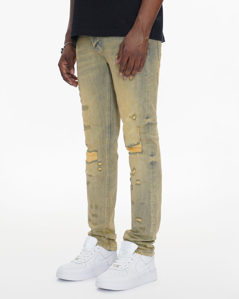 Person wearing beige distressed jeans and white sneakers on a white background