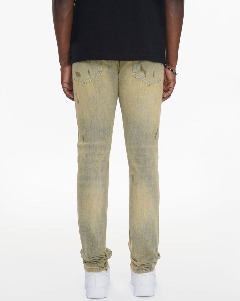 Person wearing beige distressed jeans on a white background