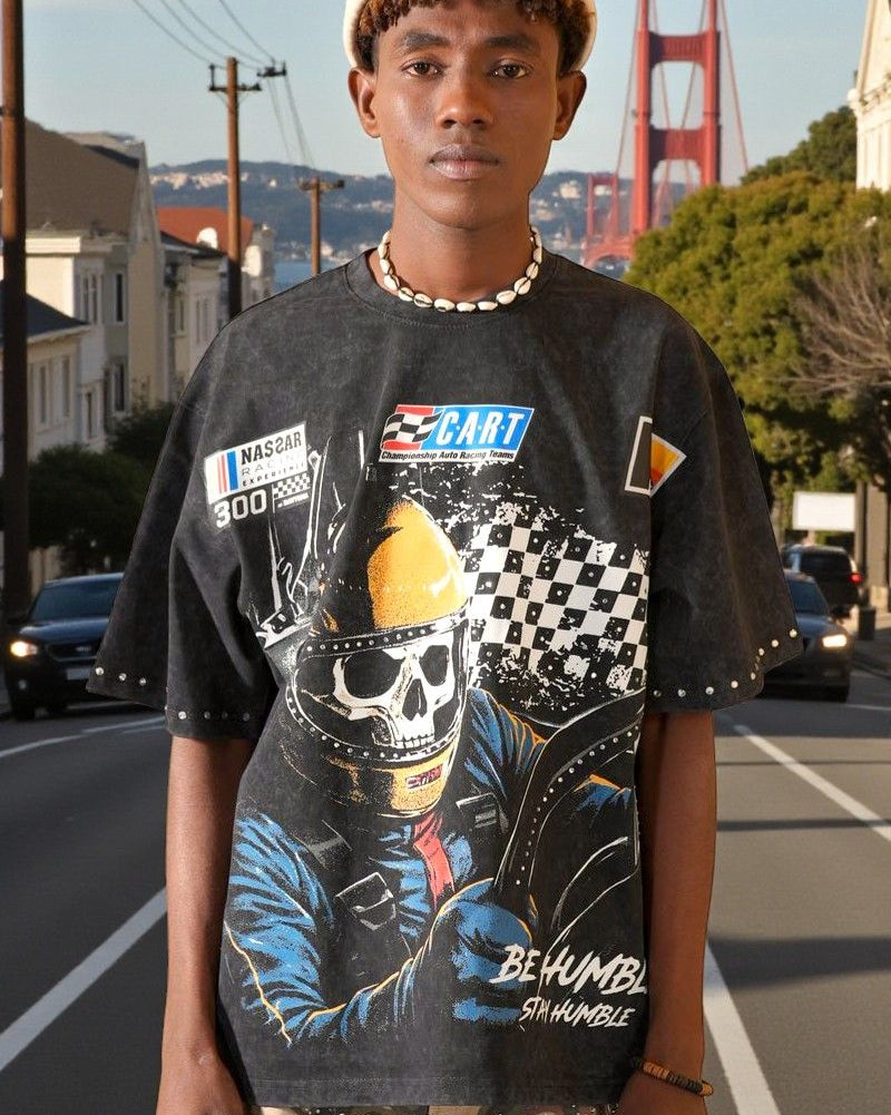 Person wearing a graphic t-shirt with a skull and racing helmet design, standing on a street with the Golden Gate Bridge in the background.