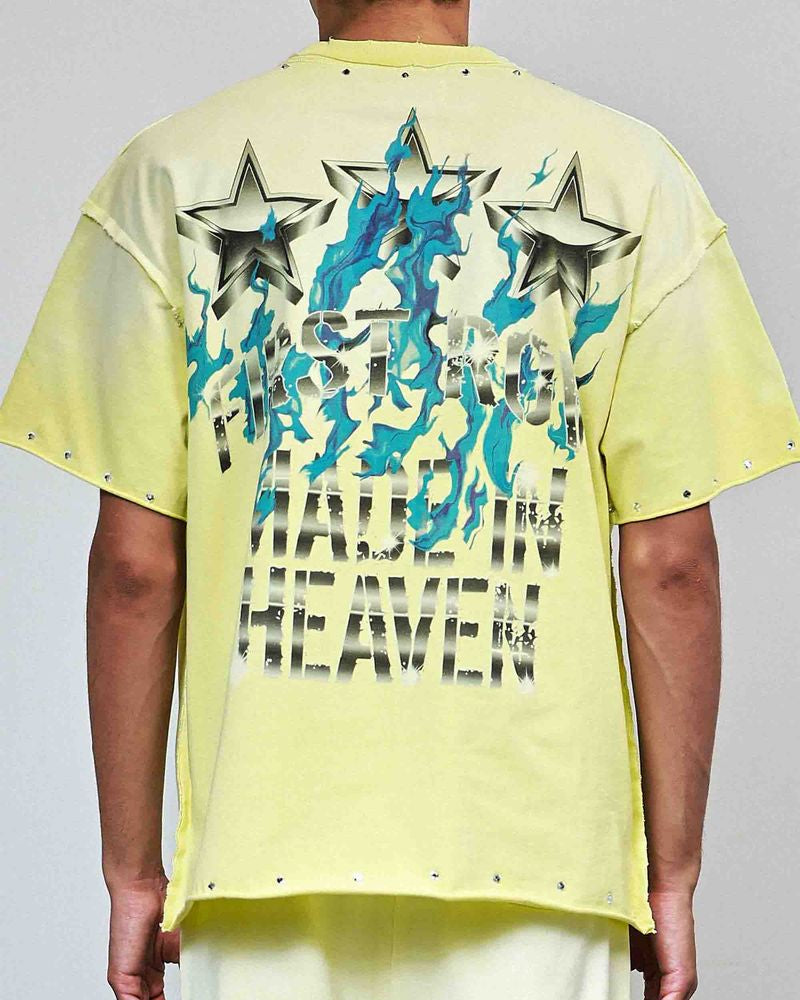 Person wearing a bright yellow t-shirt with star designs and text on a plain background