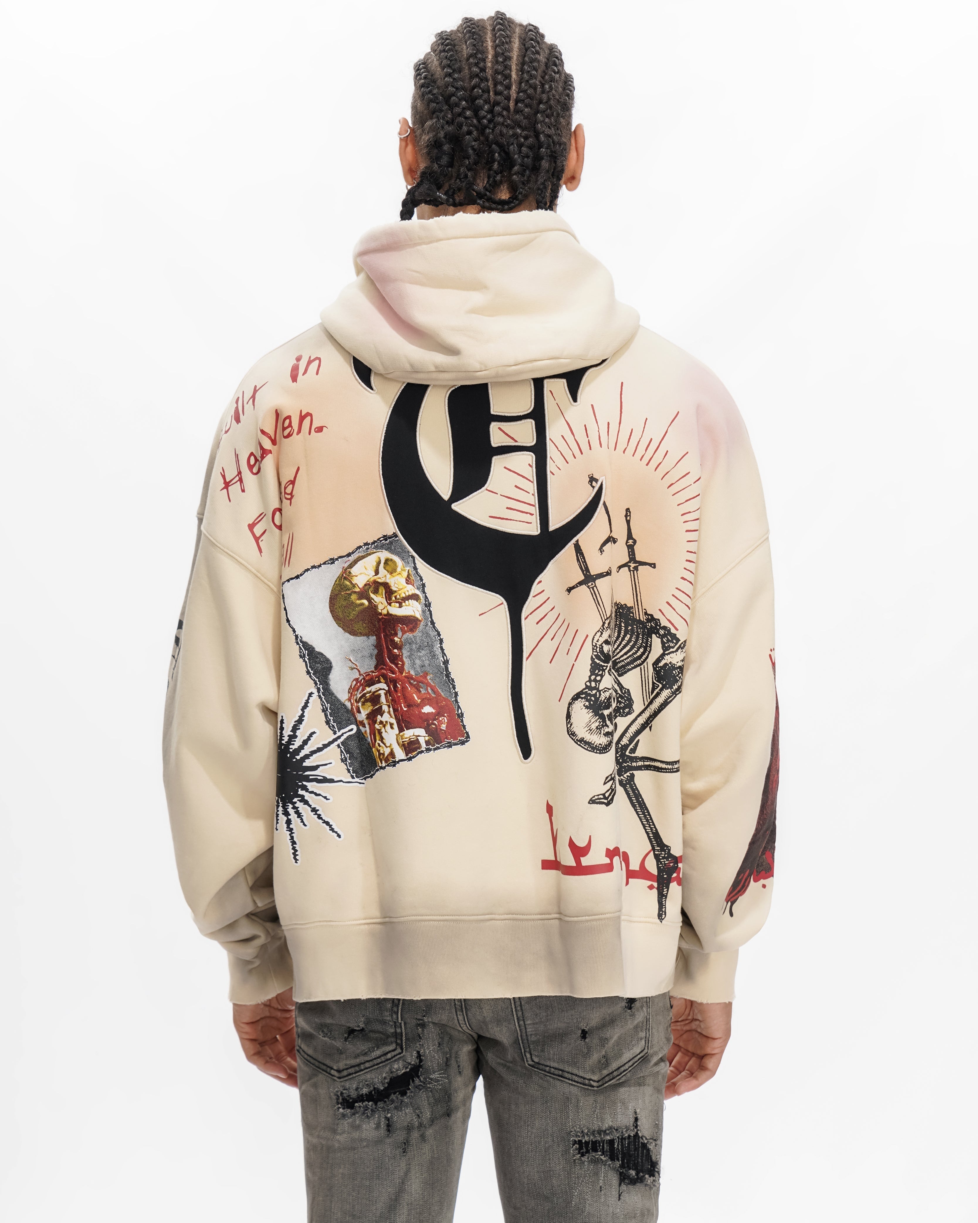 Person wearing a cream hoodie with black and red graphics on the back, standing against a white background.