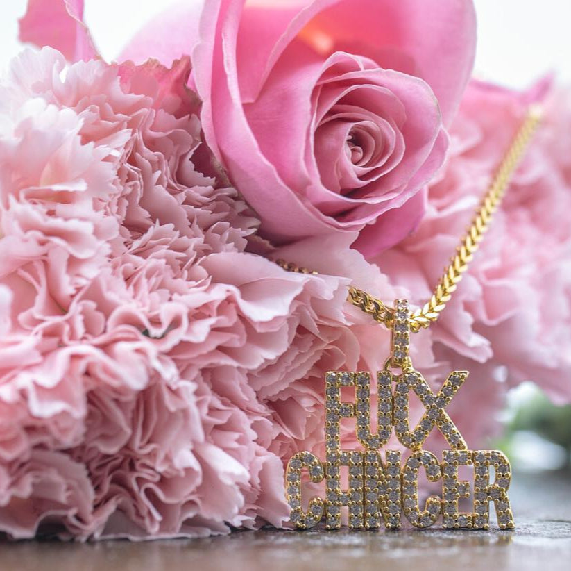 Gold necklace with 'FUCX CANCER' pendant on pink flowers