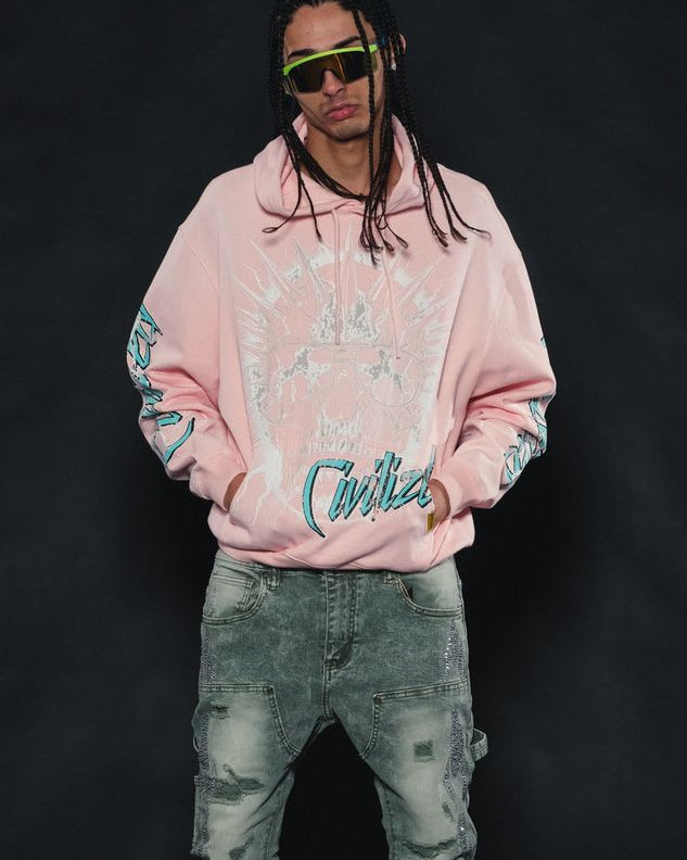 Person wearing a pink hoodie with floral patterns and text, light blue jeans, and white sneakers on a black background.