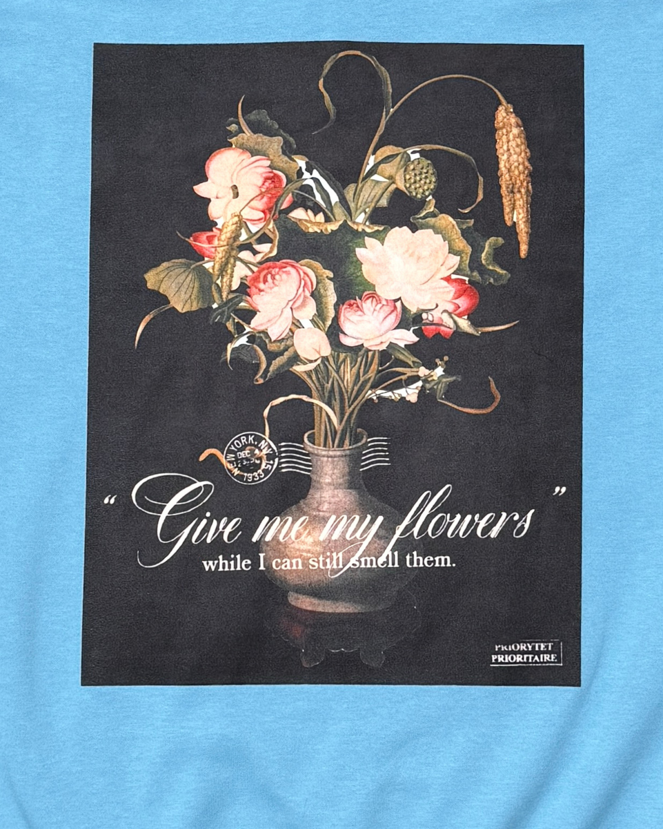 Floral design with a vase on a black background, featuring text on a blue shirt.