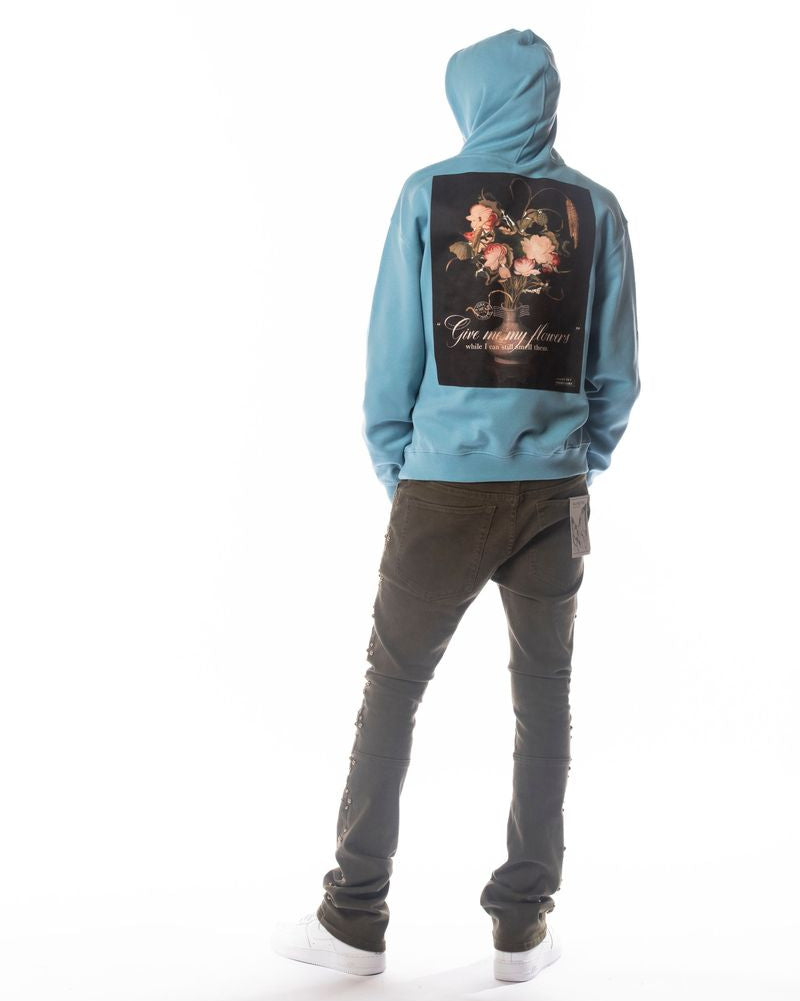 Person wearing a blue hoodie with a floral design on the back, standing against a white background