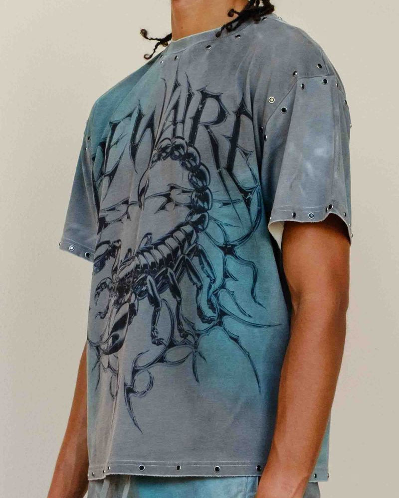 Person wearing a blue graphic t-shirt with a design on a plain background