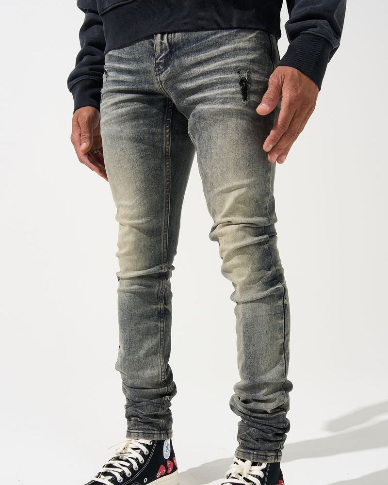 Person wearing distressed gray jeans and black sneakers on a white background