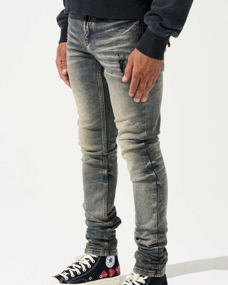 Person wearing distressed gray jeans and black sneakers with red accents on a white background