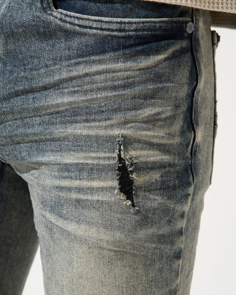 Close-up of a distressed denim jeans with a white background