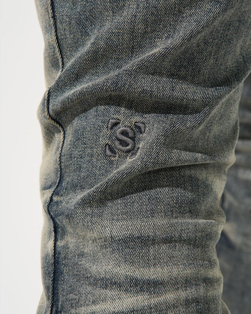 Close-up of a gray denim fabric with a brand logo on a white background