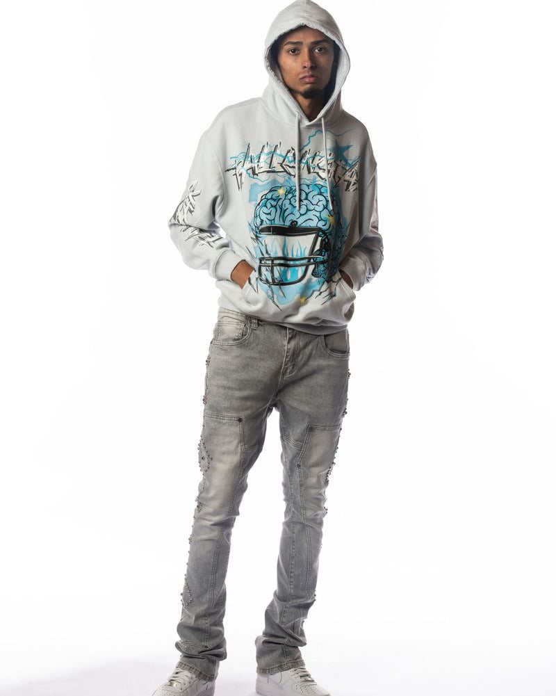 Person wearing a gray hoodie with a graphic design and gray jeans on a white background