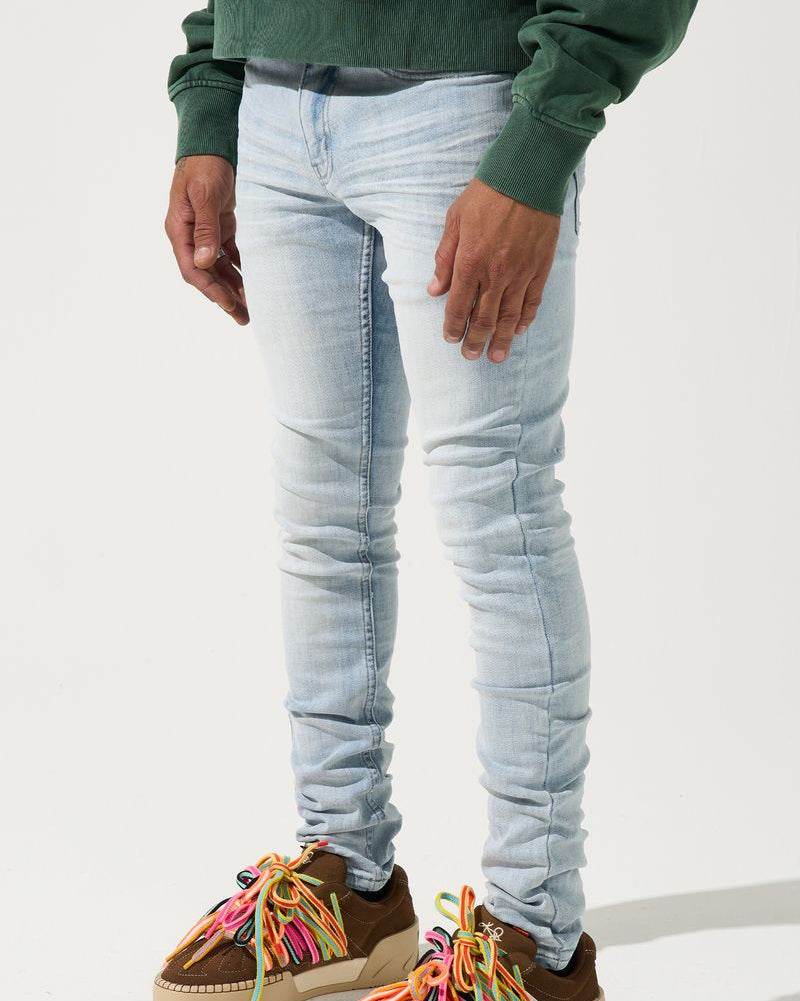 Person wearing light blue jeans and brown shoes with colorful laces on a white background
