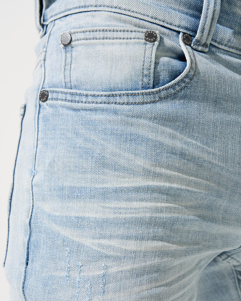 Close-up of light blue denim jeans with stitching details on a white background